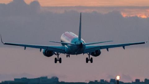 Generic image of a plane taking off over a tarmac amidst a sunset