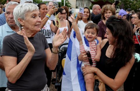 A child, with an Israeli flag draped around its shoulder and  two women celebrate  in Tel Aviv, Isreal