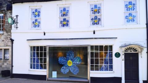 A wide shot of the museum with the blue flowers shown in each of the windows of the building