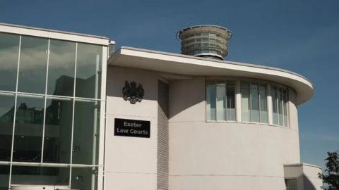 A large white building with a glass atrium. It has a sign reading Exeter Law Courts.