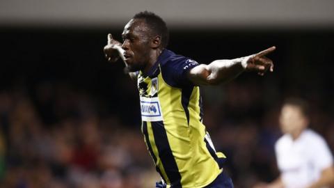 Usain Bolt spreads his arms wide to celebrate scoring a goal