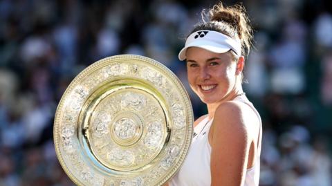 Linda Noskova holds up the Wimbledon trophy