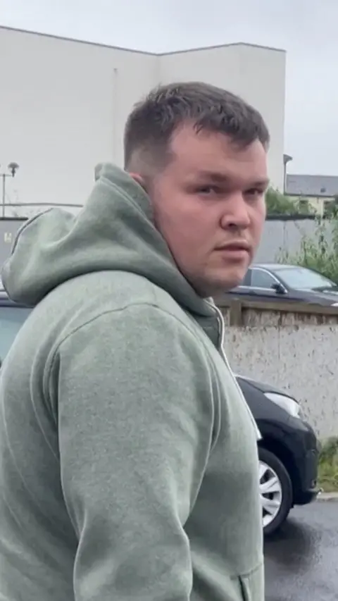 A man with a green hoody looking at the camera