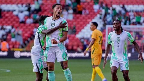 Femi Azeez in a green and white Nigeria kit jumps to celebrate a goal against Zimbabwe
