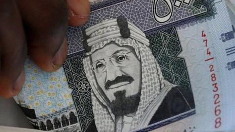 A Saudi man shows Saudi riyal banknotes at a money exchange, in Riyadh, Saudi Arabia (30 January 2016)