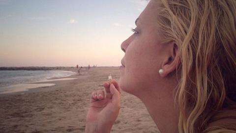 A woman smoking a cigarette on the beach