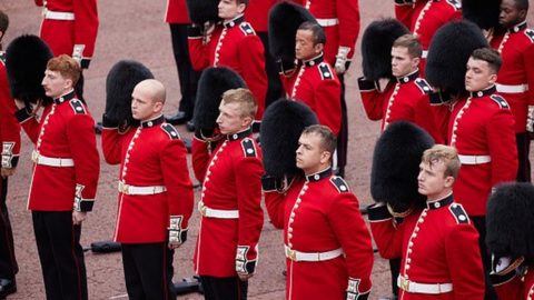 Members of the Coldstream Guards raise their Bearskin hats as they salute the new King