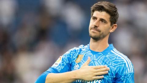 Thibaut Courtois puts his hand on the Real Madrid badge on his shirt