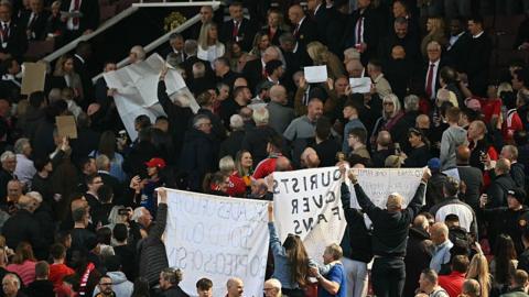 Manchester United fans holding banners up towards the directors' box at Old Trafford in April 2025 in protest at being moved from their seats