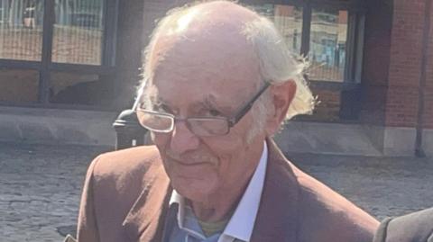 Keith Edwards outside Nottingham Magistrates' Court wearing a suit and glasses