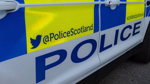 Side view of a Police Scotland car featuring a close up of the driver's side of the vehicle featuring the force's X handle and website 