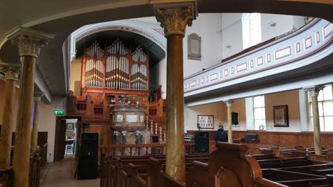 Inside Wainsgate Baptist Chapel, including pews, ornate columns and an organ