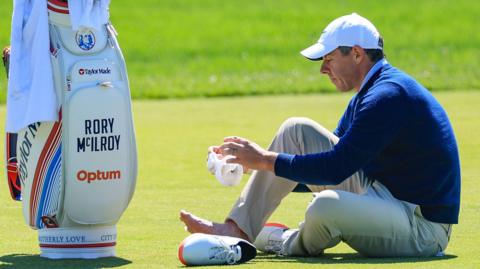 Rory McIlroy attending to his sore toe while on the third fairway at Aronimink Golf Club