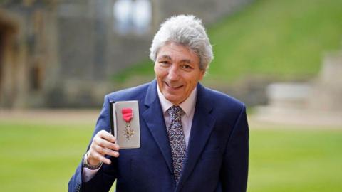 Paul Mayhew-Archer poses with his medal after being appointed a Member of the Order of the British Empire (MBE) following an investiture ceremony at Windsor Castle in Windsor, west of London on November 30, 2021, for services to people with Parkinson's disease and cancer.