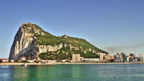A wide shot of the rock of Gibraltar with the sea in the foreground.