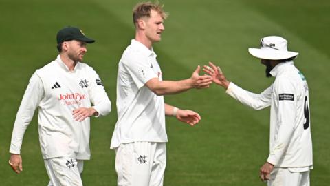 Dillon Pennington (centre) is congratulated by captain Haseeb Hameed (right, wearing a white floppy hat) as another Notts fielder (left) comes towards them