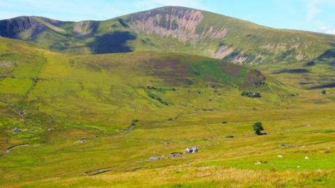 Hafodty farmhouse viewed from Llanberis path to Snowdon, with Moel Eilio peak and ridge towering above the landscape