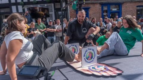 Two women locking their feet together competing in the annual World Toe Wrestling Championship in Fenny Bentley