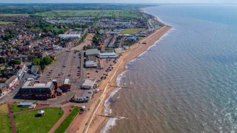 A drone image shows the coastline at Hunstanton, where you can also see a big car park, seafront buildings and a long beach