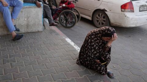 A woman crouches on the ground in despair in Deir al-Balah, central Gaza on 3 April