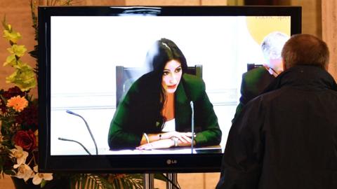 Man watches finance committee - chaired by Emma Little-Pengelly - on TV screen at Stormont, 23 August 2016