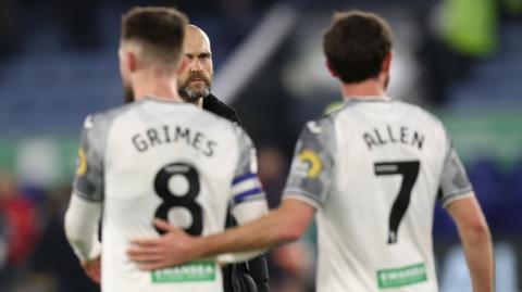 Swansea City captain Matt Grimes (L) is embraced by Joe Allen as Luke Williams (C) looks on