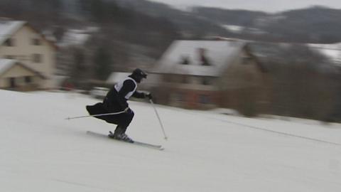 A priest in a cassock skis past