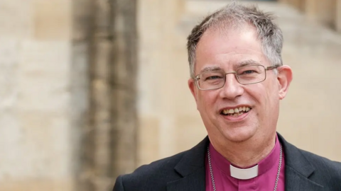 A picture of the Bishop of England, who is wearing a pink shirt and a white dog collar.