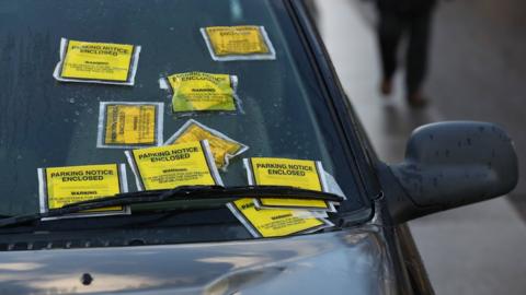 Nine parking tickets on a car windscreen