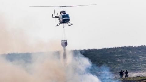 Helicopter drops water on fire