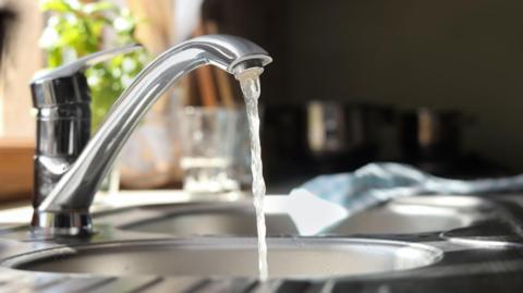 Stock image of water running from a stainless steel tap.