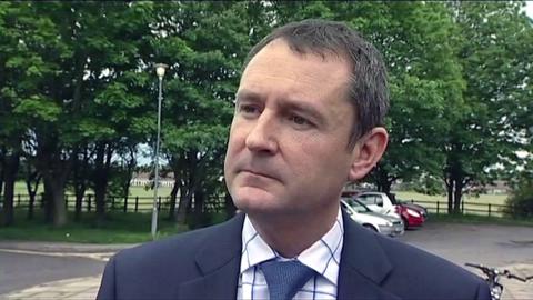 Matthew Wright is wearing a suit and looks serious as he is interviewed in a previous broadcast
