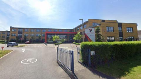 Winterbourne Academy in South Gloucestershire. It is a brown brick building with a red porch. 