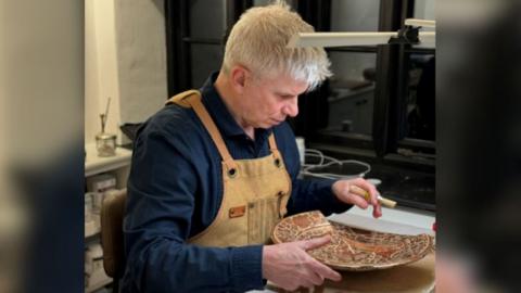 Conservator Duncan McCall working on an ancient roman plate