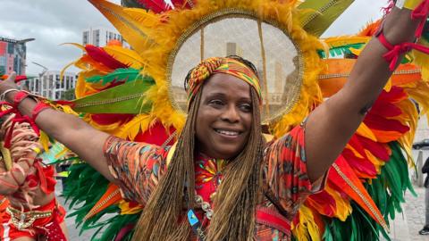 A woman in a feather headdress and bright clothing during a Caribbean festival parade