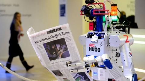 A robot holds a newspaper during a demonstration during the World Economic Forum (WEF) annual meeting in Davos, on January 22, 2016.