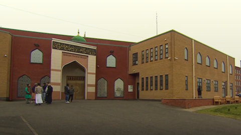 Worshippers gather and talk outside the mosque