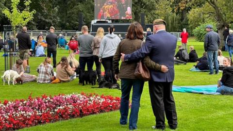 A couple embrace watching the Queen's funeral