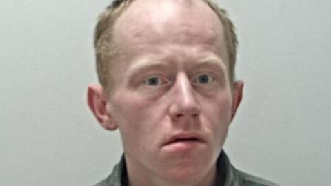 Police mugshot of Alan Morris, who has receding strawberry blond hair and blue eyes.