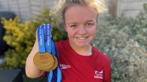Maisie Summers-Newton holding her 2022 World Championships medals