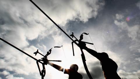 two archers in silhouette aiming bows