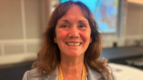 Diane Kelsey MLC smiles at the conference. She has long brown hair and wears a grey suit jacket.