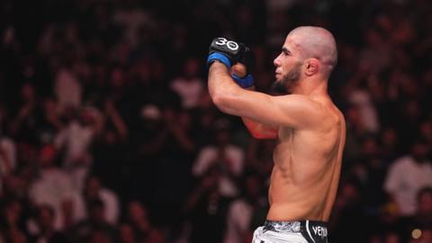Muhammad Mokaev celebrates on top of the octagon