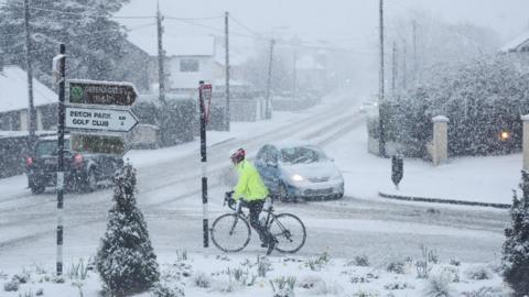 A person cycles in snowy conditions in Rathcoole in Dublin.