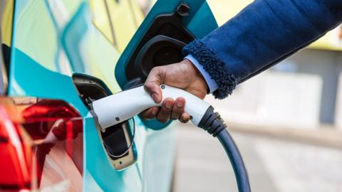 A man plugs a car in for charging electronically