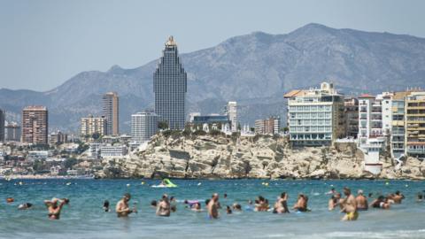 Benidom, people in the sea with a cityscape behind them