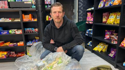 Trading Standards officer Paul Leighton in a shop with a plastic bag of vapes