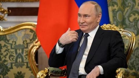 Putin sat on a chair with gold background.