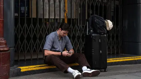  A man sits with his suitcase next to the closed entrance to Covent Garden underground station on June 4, 2026 in London