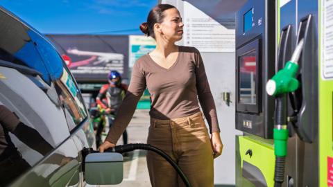 Woman at petrol pump fills up car 